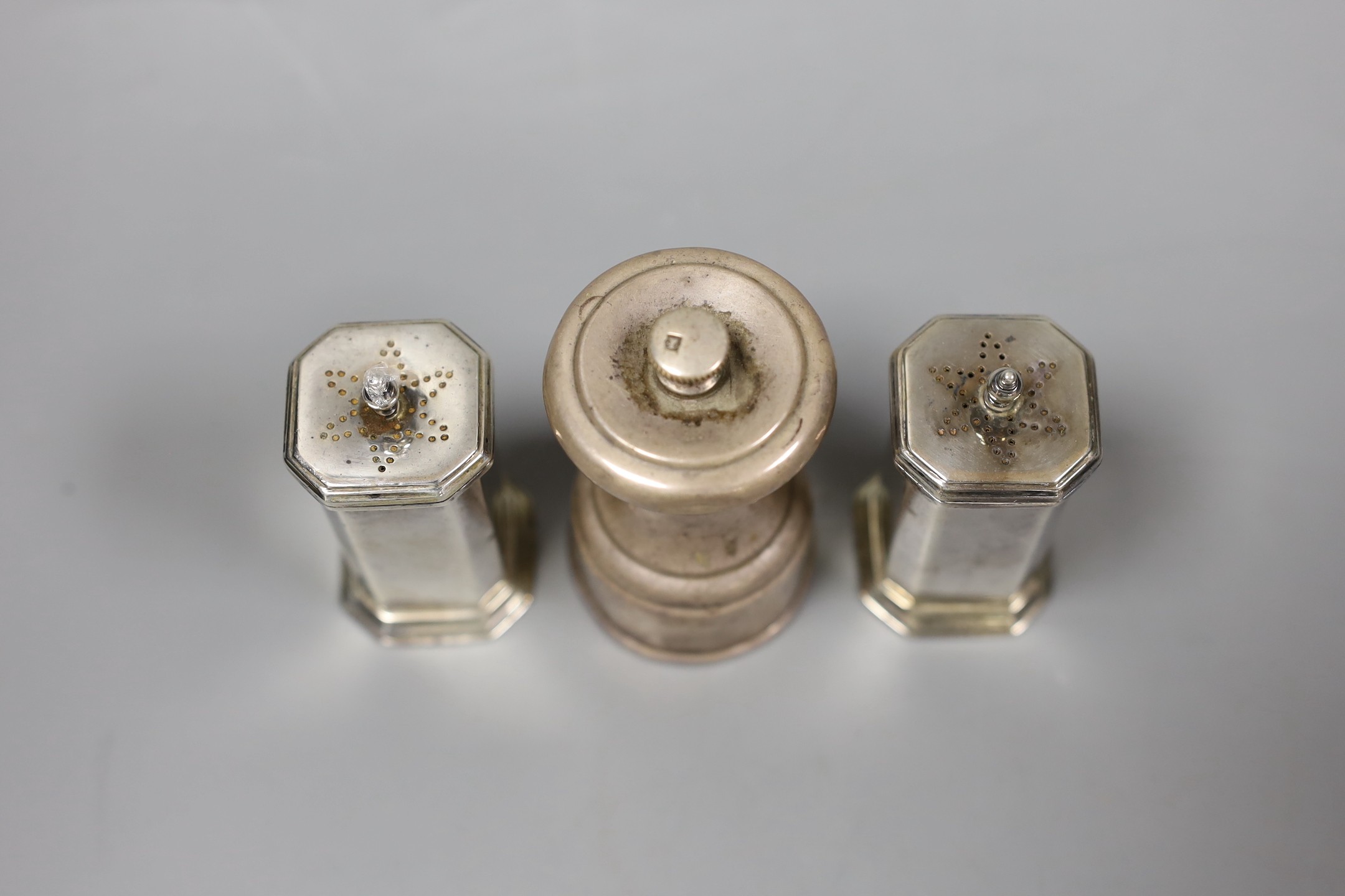 A pair of George V silver pepperettes, Birmingham, 1922, 72mm and a late Victorian silver pepper mill, Hukin & Heath, London, 1896.